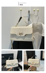 Detail of white woven crossbody bag showing metal turn-lock and top handle texture