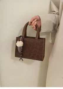Detail einer braunen Tasche mit Leopardenprägung und Plüsch-Eiscreme-Anhänger