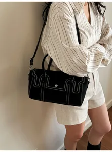 Detail view of black handbag with white contrast stitching and silver metal buckle closure