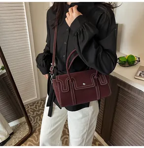 Detail of dark burgundy leather handbag with contrasting white stitching and silver hardware