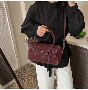 Detail of burgundy tote bag showing white contrast stitching and matte leather texture