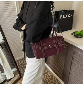 Fashionable burgundy suede handbag with white contrast stitching shown in a chic urban setting