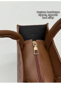 Makroaufnahme des goldenen Reißverschlusses an einer braunen Ledertasche mit glatter Führung