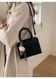 Schicke Handtasche mit Leopardenmuster, Rundgriff und Plüsch-Anhänger am Modell gezeigt