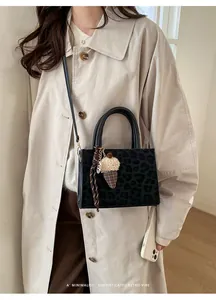 Detail der Handtasche mit Leopardenmuster, Plüsch-Anhänger und Flechtriemen
