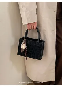 Details der schwarzen Totebag mit Leopardenprägung, Eismotiv-Anhänger und Handgriffen