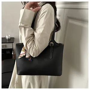 Detail of black PU leather tote bag with white stitching and decorative silk scarf