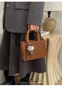 Detail der Handtasche mit Leopardenmuster, Rundgriffen und Plüsch-Eiscreme-Anhänger