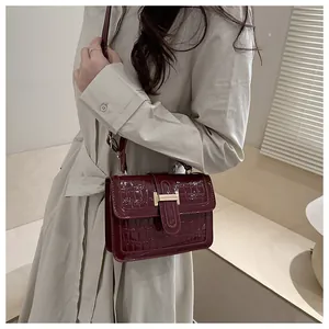 Détail du sac à main bordeaux motif crocodile avec boucle en H dorée et cuir verni