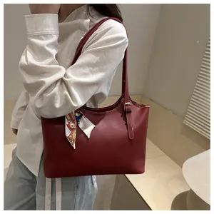 Detail of burgundy leather tote bag featuring contrast stitching and colorful silk scarf