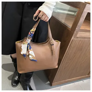Detail of caramel tote bag featuring a decorative silk scarf and precise stitching