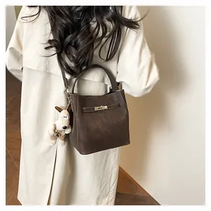 Detailweergave van de donkerbruine bucketbag met metalen gesp op een schouder