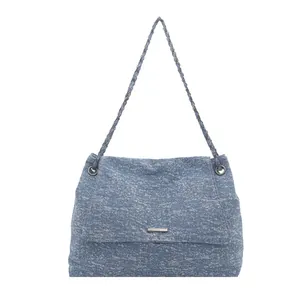 Blue denim tote bag with chain strap and rectangular metal logo on white background