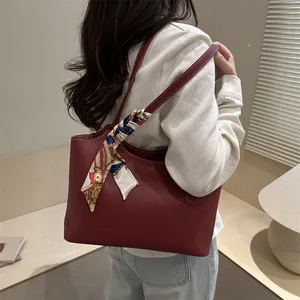 Deep red matte leather tote bag with contrast stitching and decorative scarf on handle