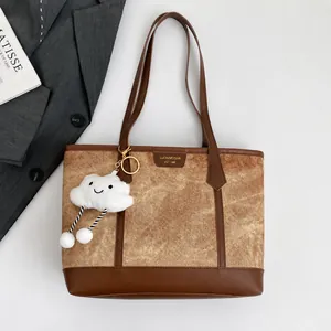 Macro shot of the brown tote bag material with a cute white cloud pendant and branding