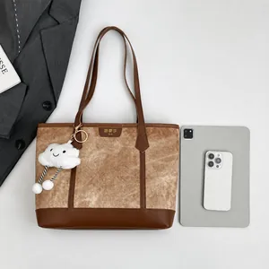 Top view of a large vintage tote bag with plush charm and electronics for commuting