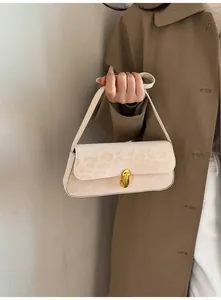 Detail van crème baguette tas met subtiele luipaardprint en gouden ovale metalen sluiting