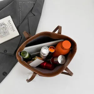 Top view of large brown leather tote bag interior showing laptop and daily essentials