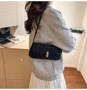 Detailweergave van de zwarte baguette tas met luipaardprint en gouden hoefijzer gesp