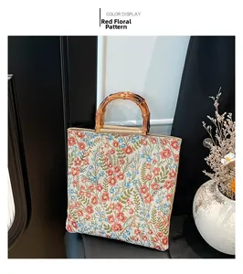 Detalle del bolso tote de algodón y lino con bordado floral rojo y asa de bambú