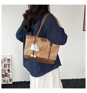 Detail of tan vintage tote bag with deep brown leather handles and a plush cloud charm