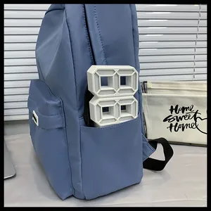 Dettaglio dello zaino in nylon blu con tasche laterali e consistenza opaca in ambiente domestico