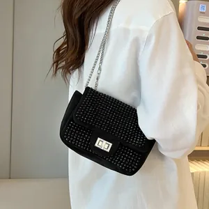 Detail of black rhinestone crossbody bag featuring silver chain and metal twist lock