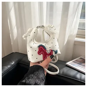 Detail der weißen Mini-Tasche mit schwarzen Herzpunkten und rotem Strick-Pferdeaufnäher
