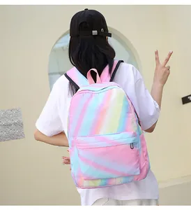 Rear view of a girl wearing the rainbow gradient waterproof backpack against a white wall