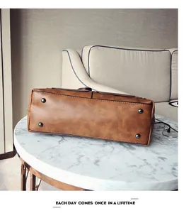 Close-up of brown vintage PU leather bag base with four protective metal feet on a table