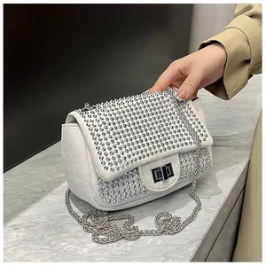 Close-up of sparkling rhinestones and silver twist lock on beige crossbody bag