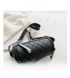 Detail of black quilted cylinder bag with double zippers and wide adjustable strap