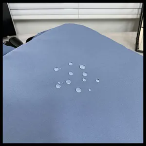 Dettaglio del tessuto in nylon blu con effetto impermeabile e gocce d'acqua sullo zaino