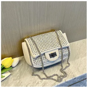 Detail of elegant ivory chain bag with sparkling silver rhinestones and metal lock