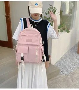 Pink canvas backpack for students shown on a model with multi-pocket design detail