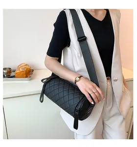 Quilted black cylinder crossbody bag with wide strap shown on a model for casual style