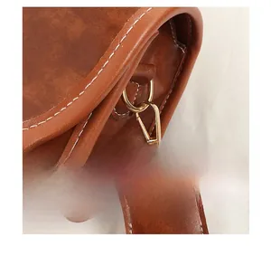 Détail du sac vintage marron avec boucles métalliques et surpiqûres blanches