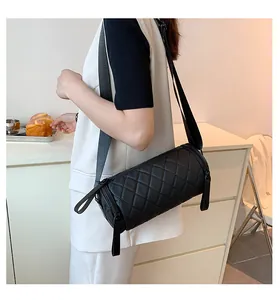 Close-up of quilted diamond pattern on black cylindrical crossbody bag with wide strap
