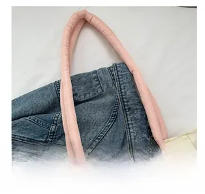 Dettaglio dei manici imbottiti rosa su una borsa tote in tela bianca con occhielli