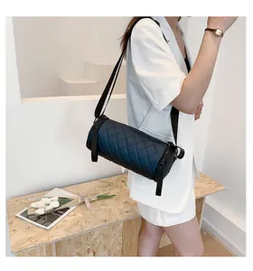 Detail of black quilted barrel bag worn with adjustable shoulder strap by model