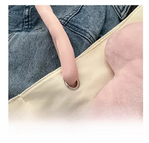 Dettaglio della borsa tote in tessuto beige con occhielli in metallo e manico rosa