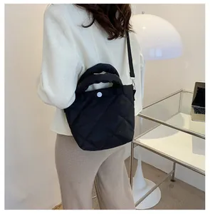 Details einer schwarzen Stepptasche mit weißem Knopfverschluss und abnehmbarem Gurt