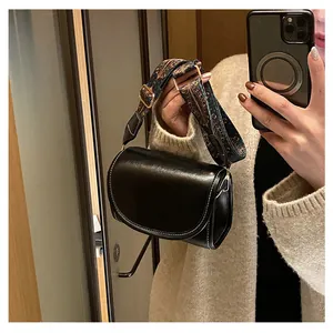 Détail d'un sac bandoulière demi-lune noir avec une large sangle tissée au style vintage