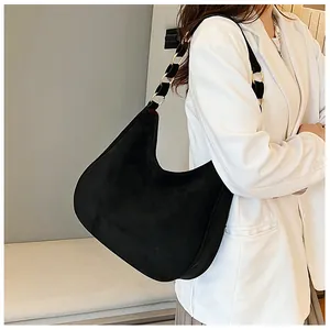 Detail van zwarte suède hobo tas met goudkleurige ringband gedragen op de schouder