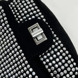 Detailed macro view of black suede evening bag featuring sparkling silver rhinestones and metal lock