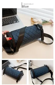 Detail view of the blue quilted cylinder bag with wide woven strap and zipper closure