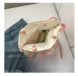 Interno spazioso della borsa tote beige con ombrello, libro e peluche inclusi