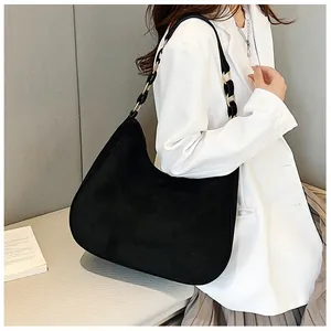 Detail van zwarte matte suède hobo-tas met decoratieve gouden metalen ringen aan de riem