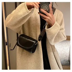 Détail d'un sac bandoulière noir avec coutures blanches et large sangle florale