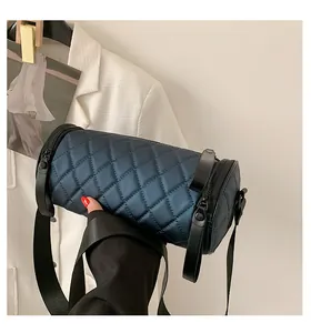 Close-up of quilted cylinder bag texture with wide strap against white blazer